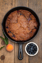 Cast iron blueberry peach cobbler on an antique wood table