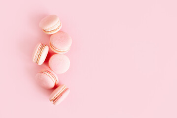Tasty french macarons on a pink pastel background.