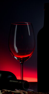 .Conceptual photo of wine bottle and glass on red background.