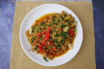 Stir fried basil with minced pork on white dish on sackcloth on black background.street food 