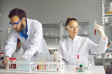 Team of Medical Research Scientist Conducts Experiments in Laboratory with Microscope, Test Tubes, Micropipette and other equipment.