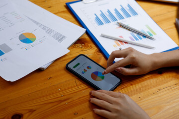 Close up of Accounting business woman working on smartphone note laptop computer and analyzing real estate investment data, Financial and tax systems concept.