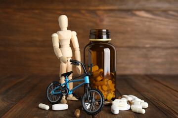 Pills, sportsman and bike model on wooden background. Using doping in cycling sport concept