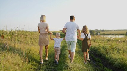 View of a beautiful cheerful family walking with children, spending daytime in a cottage town on weekends outdoors. In the summer, a happy family walks in the cottage village.