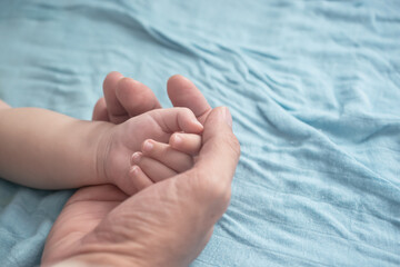 Close up of father holding baby hand, soft focus.