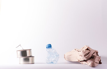 Isolated and pressed daily use recyclable items composition over white; aluminium box, plastic water bottle and paper. Includes Copy Space.