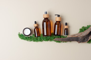 Skin care products on pastel beige background with moss, wood. Flat lay, copy space.