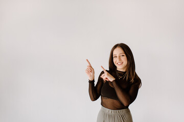 Smiling young woman pointing towards wall