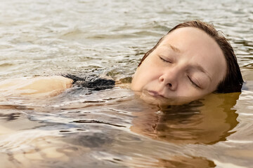 Portrait of a young woman close-up in the water. Swimming in the lake