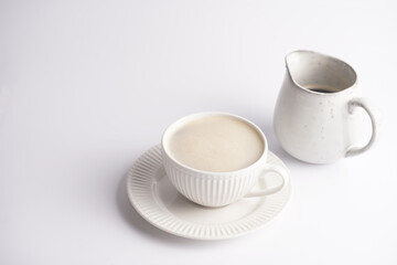 A white porcelain cup with coffee drink cappuccino on a white saucer plate on a white surface
