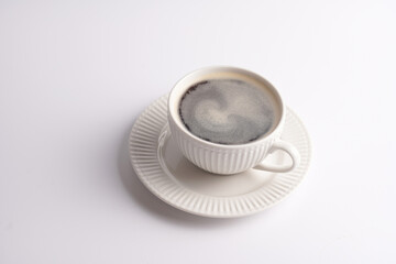 A white porcelain cup with coffee drink cappuccino on a white saucer plate on a white surface