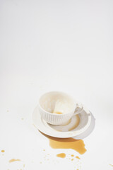 An empty cup with coffee drink on a white saucer plate on a white surface