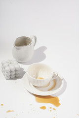 An empty cup with coffee drink on a white saucer plate on a white surface surrounded by bubble candles
