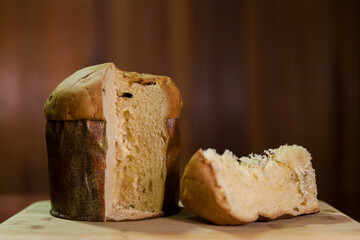 Panettone slice on the table. Panettone cut on wooden table and textured background. Panettone concept. Chocotone concept.
