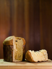 Panettone slice on the table. Panettone cut on wooden table and textured background. Panettone concept. Chocotone concept.
