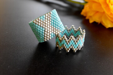 Two beaded rings on a black surface.