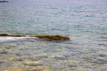 Big stone close-up on the background of the sea. Group of large stones. Boulders are standing in the beautiful water. Rocky seaside coast.