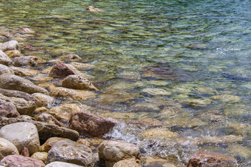 Big stone close-up on the background of the sea. Group of large stones. Boulders are standing in the beautiful water. Rocky seaside coast.