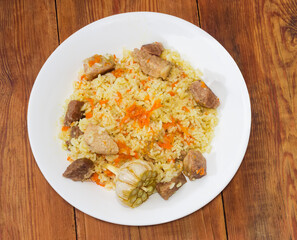 Cooked pilaf on dish on old rustic table, top view