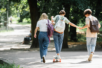 Teen boy holding hand of friend on skateboard in park