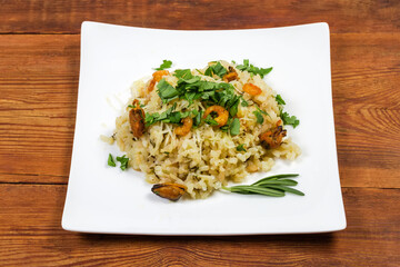 Risotto with seafood on square dish on rustic table
