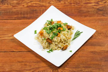 Serving of risotto with seafood on dish on rustic table