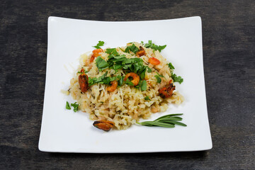 Risotto with seafood on square dish on a dark surface