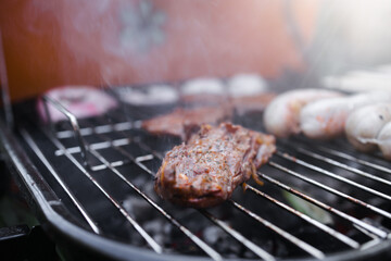 View of the grill with beef steaks, sausages and vegetables. meat and sausages are grilled on the grill. Spend time with your family at the grill. Social meetings, friends. Red grill with kindling