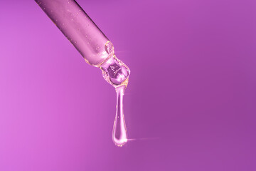 A drop of serum from a pipette with highlights from the light.
