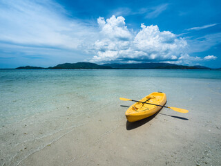 Yellow kayak on white sandbank with crystal clear water of tropical island with fluffy cloud blue sky background. Koh Mat Sum Island, Near Koh Samui, Thailand.