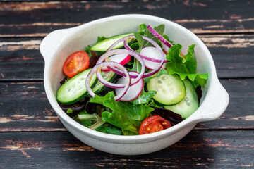 Vegan salad of vegetables for a diet, in a plate, on a wooden vintage background. Close-up.