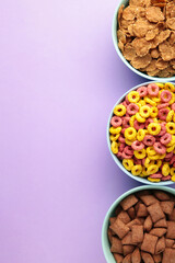 Variety of cereals in blue bowls, quick breakfast on purple background. Vertical photo