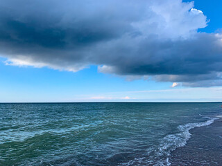 Fototapeta na wymiar Big dark cloud in the blue sky at the seaside, sea horizon, natural sea background