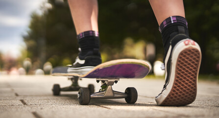Unrecognizable teenager girl starting skateboarding on a road in a park - Wanderlust and skateboarder outdoor lifestyle concept © PEOPLEVISUALS