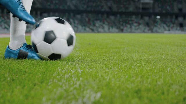Unrecognizable female dribbling soccer ball on side of a field of a huge stadium