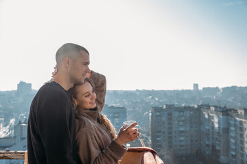 Young couple drinking coffee on the balcony of the apartment in the morning. Young happy couple,...