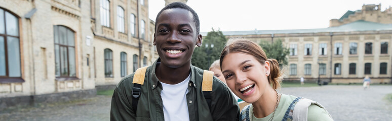 Smiling interracial students looking at camera outdoors, banner