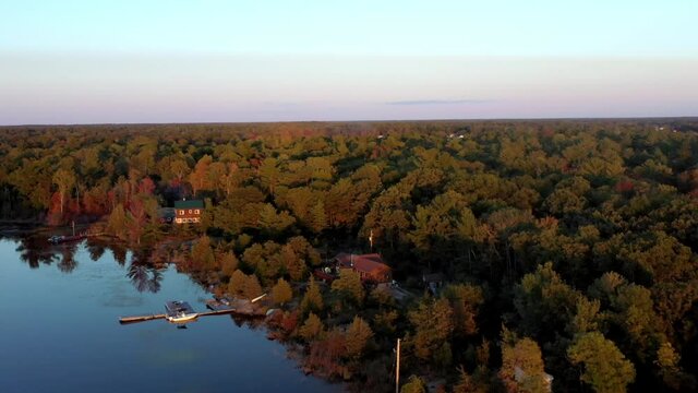 Flying over calm water on a relaxing golden sunset at golden house with land in sight surrounded by islands in idyllic location