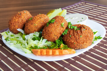 Traditional middle Eastern chick pea based felafel on a plate with pickles and turnip