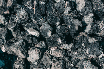 Repair of the road surface. A pile of stones made of old asphalt lies on the road. Textured abstract background. Close-up