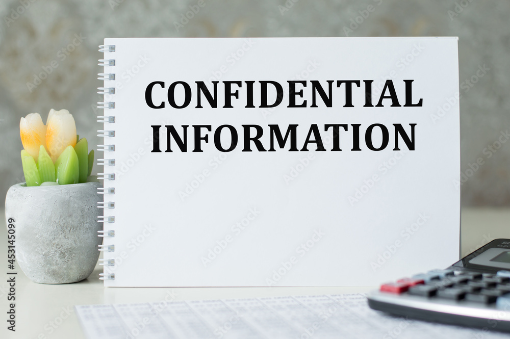 Poster notebook with text confidential information on table next to calculator, business concept
