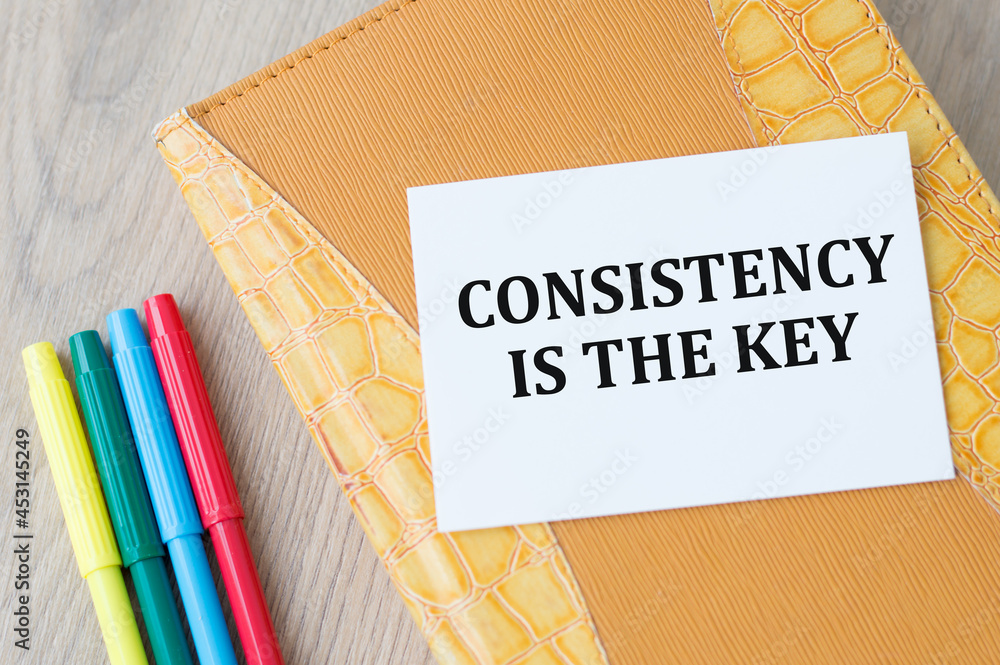 Poster text consistency is the key on a white card that lies on a notebook next to colored markers on a woo
