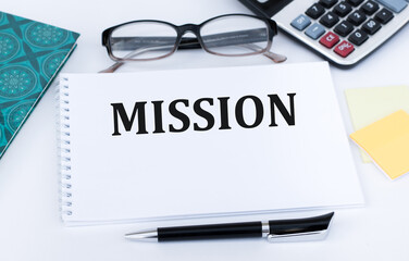 On a notebook the text of MISSION, next to the glasses and a pen on a white background