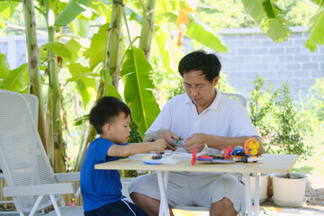 Home – based Learning (HBL), Parent sitting homeschooling with little kid, Asian Father and son...