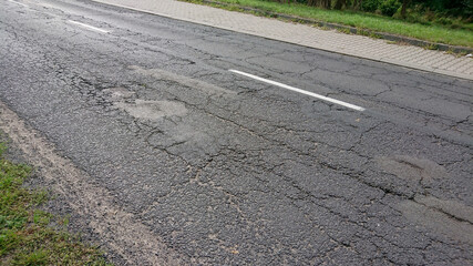 Stara, zniszczona nawierzchnia asfaltowa.