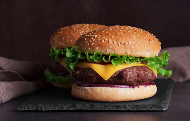 Two hamburgers on a dark background on plate of slate