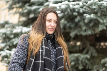 Portrait of a young beautiful long-haired girl in a winter park.