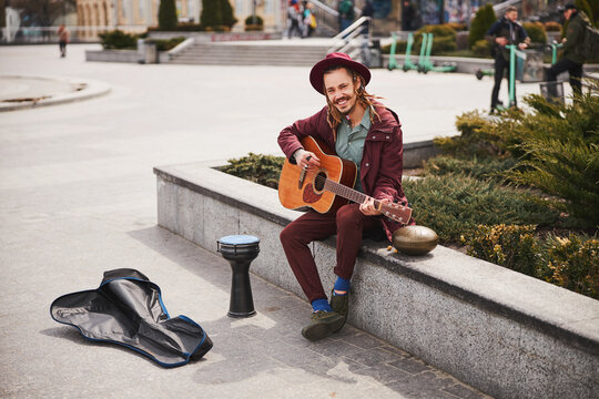 Positive delighted male person playing the guitar