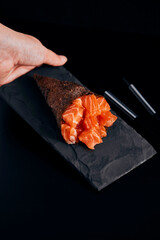 Temaki salmon on the background dark with hand