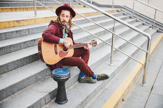 Kind hippie sitting on stairs with guitar